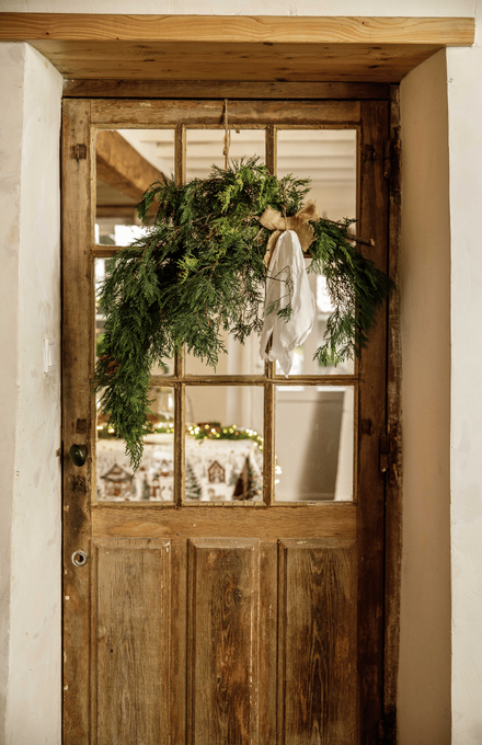 Une porte en bois décorée avec des branches de sapin