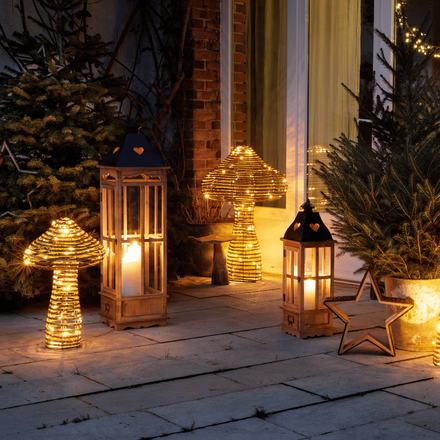 Plusieurs lanternes et lampes en forme de champignon entourées de sapins
