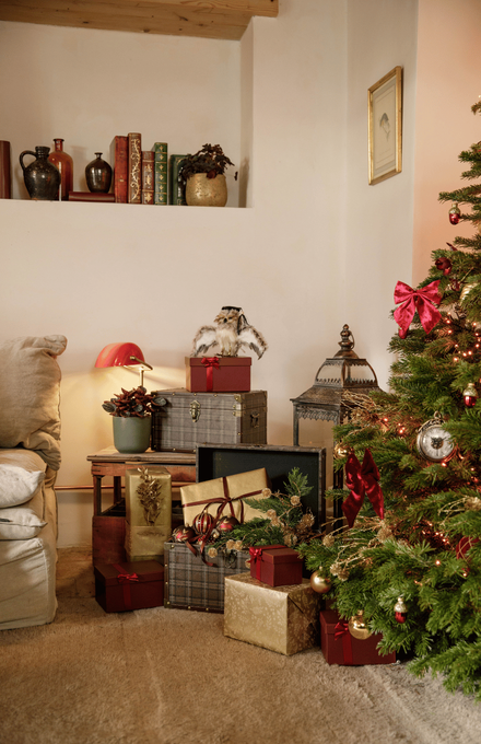 Un salon de Noël aux couleurs bordeaux et or avec une pile de cadeaux et un sapin