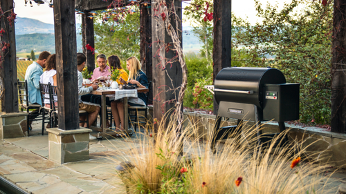 Groupe de personnes qui mangent en terrasse à coté d'un barbecue