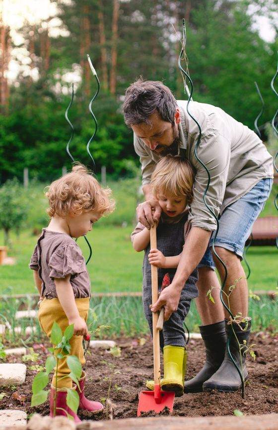 Un père et ses enfants qui jardinent au jardin