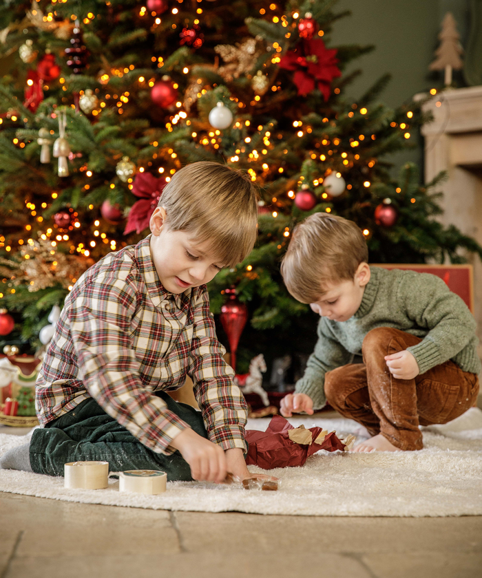 Deux enfants en train de jouer devant un sapin de Noël