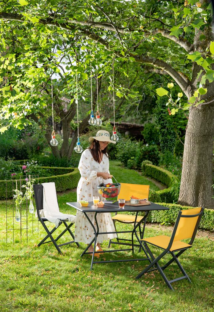 Une femme qui prépare des choses sur sa table max dans son jardin