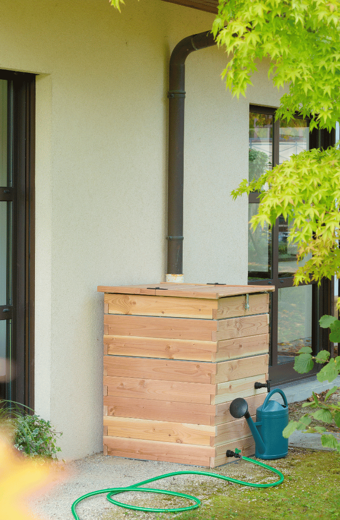 Un récupérateur à eau en bois contre une maison